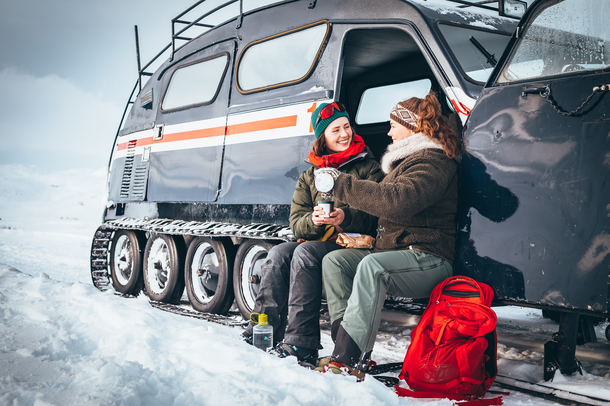 Sitting in front of a snow coach with a hot cup of tea